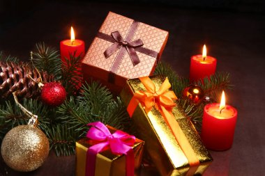 Noel dekorasyon hediye kutuları, kırmızı mumlar, Noel ağacı ve renkli topları. Seçici odak.