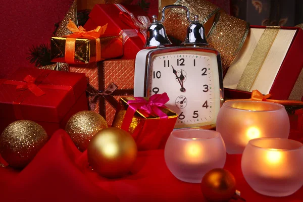 Reloj de Navidad, vaso con coñac o whisky y velas. Decoración de Año Nuevo con cajas de regalo, bolas de Navidad y árbol. Concepto de celebración para Año Nuevo . — Foto de Stock