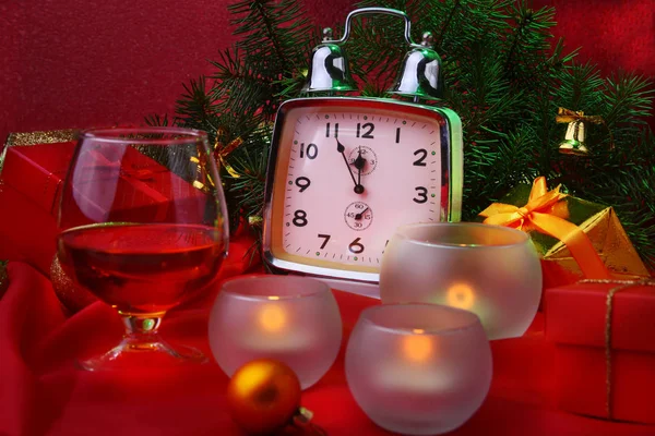 Christmas clock, glass with cognac or whisky and candles. New Years Decoration with gift boxes, christmas balls and tree. Celebration Concept for New Year.