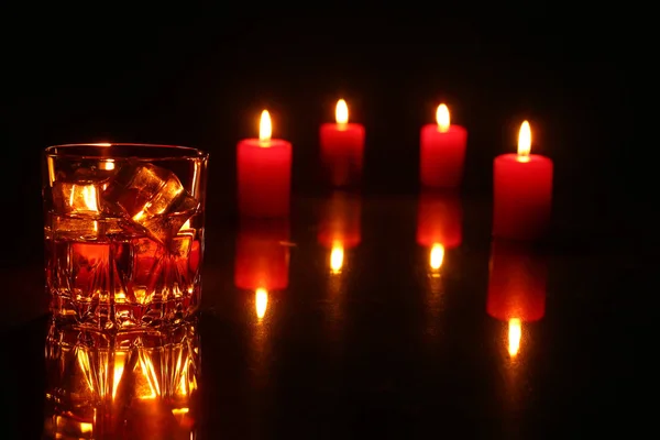 Decorazione natalizia. bicchiere di cognac o whisky, candele natalizie e confezione regalo su fondo di legno . — Foto Stock