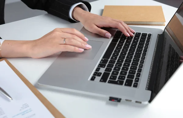 Ділова жінка працює на ноутбуці, сидячи за столом в офісі . — стокове фото