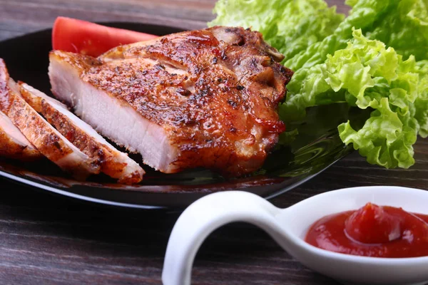 Daging babi panggang dengan tomat, daun selada dan saus tomat di atas piring . — Stok Foto