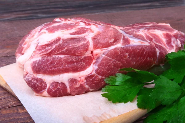 Raw pork neck chop meat with parsley herb leaves on a stone background. Ready for cooking. — Stock Photo, Image