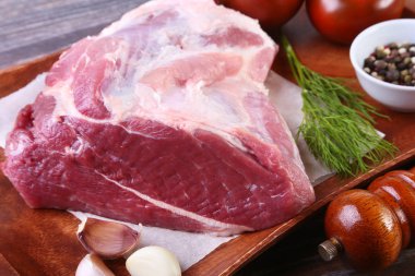 Otlar, baharatlar, domates ve biber değirmeni yemek pişirmek için hazır ahşap tahta üzerinde çiğ domuz biftek. Seçici odak