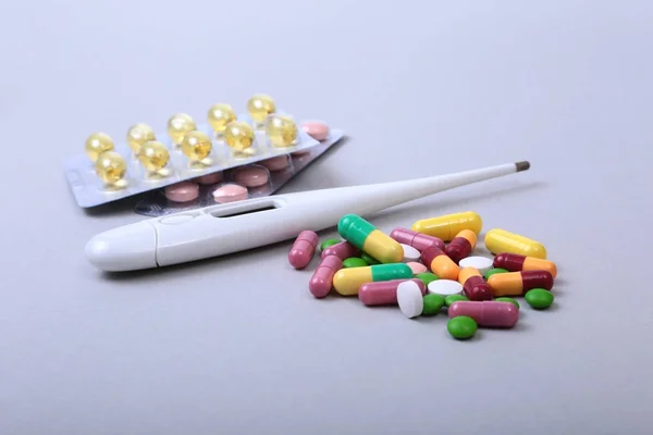 Píldoras y termómetro médico sobre fondo blanco . . — Foto de Stock