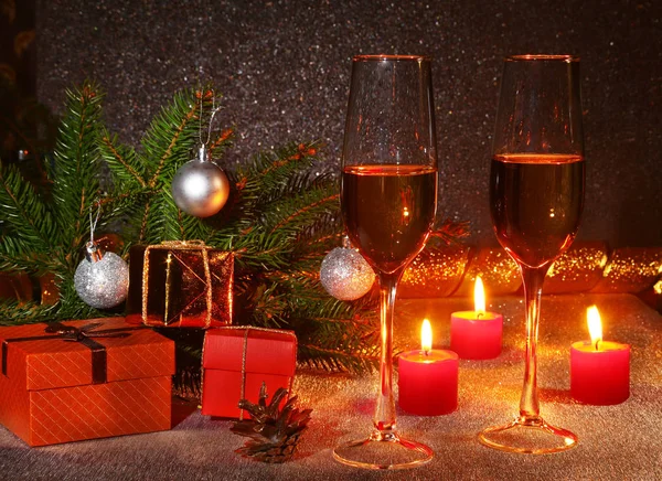 Christmas composition with Glass of sparkling champagne wine or cognac, christmas candles, colorful balls, gift box and tree on a sparkling background. New Year decoration.