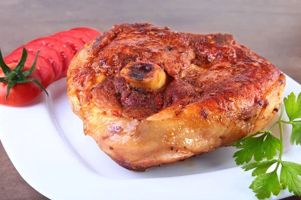 Grilled pork chop with sliced tomato and sauce on wooden table. — Stock Photo, Image