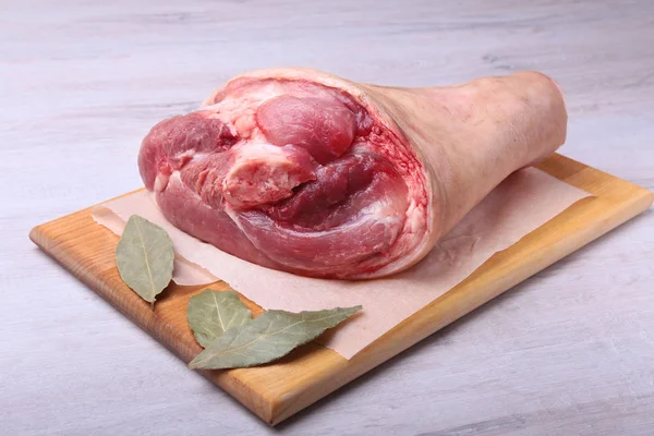 Raw pork knuckle, Aromatic dried bay leaves, garlic and spices on a cutting board. Selective focus. Ready for cooking. — Stock Photo, Image