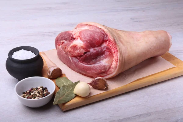 Raw pork knuckle, Aromatic dried bay leaves, garlic, sea salt and spices on a cutting board. Selective focus. Ready for cooking. — Stock Photo, Image