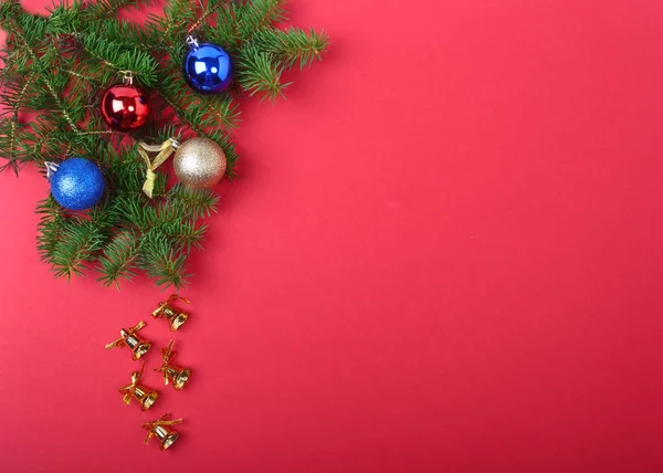 Decoração de Natal com belos sinos de ouro, bolas coloridas e fitas no fundo vermelho . — Fotografia de Stock