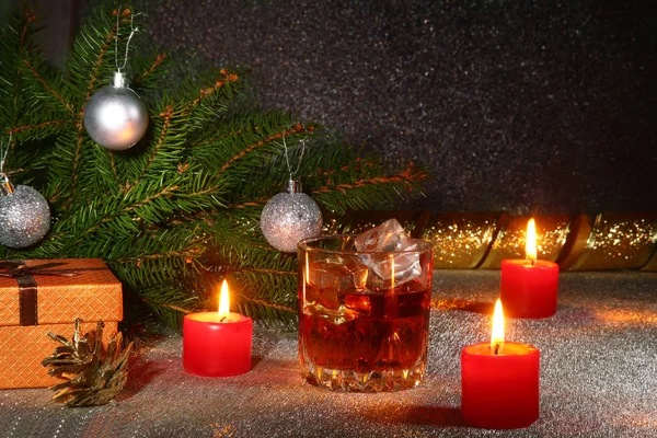 Kerstdecoratie met glas whisky of cognac, Kerst kaarsen, boom en cadeau doos op een fonkelende achtergrond. Nieuwjaar decoratie. — Stockfoto