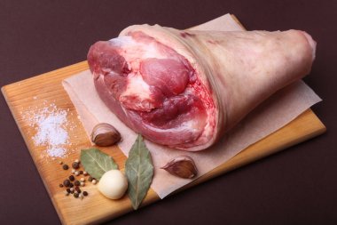 Çiğ domuz knuckle, aromatik defne yaprağı, sarımsak, deniz tuzu ve baharatları bir kesme tahtası üzerinde kurumuş. Seçici odak. Hazır yemek pişirmek için.