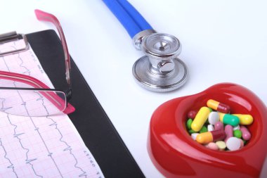 Kırmızı kalp, asorted pils, gözlük ve beyaz arka plan üzerinde bir stetoskop.