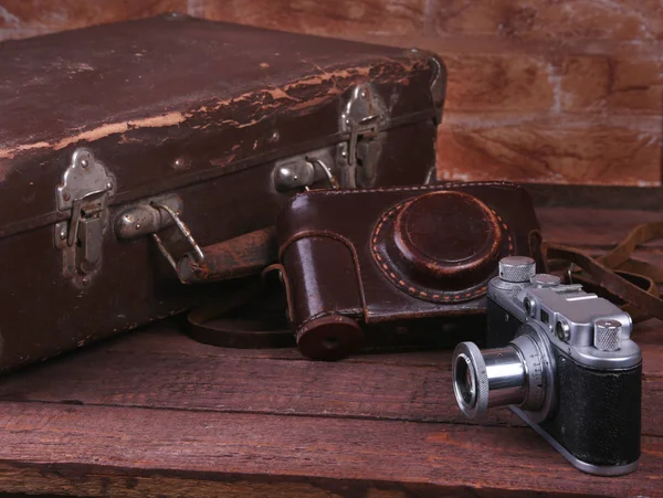 Conceito de viagem com mala vintage câmera velha no chão de madeira . — Fotografia de Stock