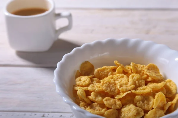 Corn Flakes cereal in a bowl, glass with milk and cap with espresso coffee. Morning breakfast. — Stock Photo, Image