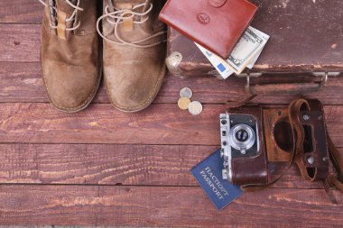 Seyahat konsepti Vintage çanta, güneş gözlüğü, eski fotoğraf makinesi, süet çizmeler, para ve pasaport ahşap zemin üzerinde case ile.