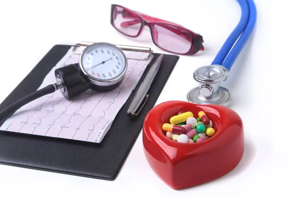 Coração vermelho, pilhas sortidas, óculos e um estetoscópio sobre fundo branco . — Fotografia de Stock