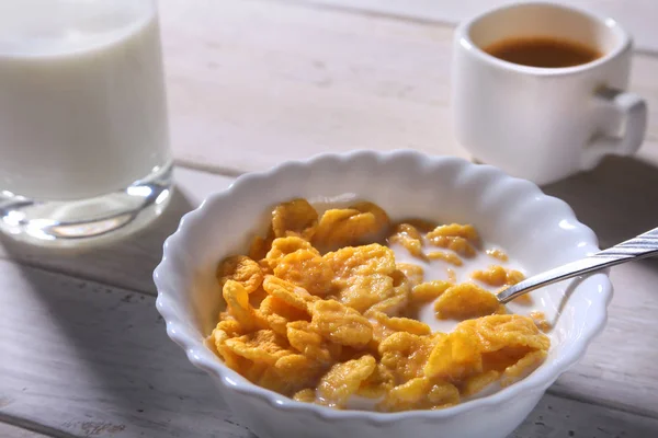Corn Flakes cereal in a bowl, glass with milk and cap with espresso coffee. Morning breakfast. — Stock Photo, Image