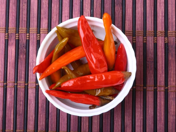 Skål med picklad röd hoade Chilipeppar på trä bakgrund. — Stockfoto