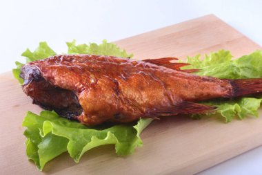 Füme balık ve beyaz arka plan üzerinde izole tahta kesme tahta üzerinde yeşil marul yaprakları limon.