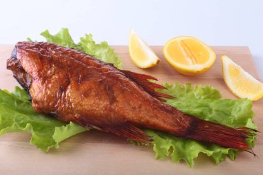 Füme balık ve beyaz arka plan üzerinde izole tahta kesme tahta üzerinde yeşil marul yaprakları limon.