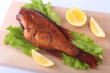 Füme balık ve beyaz arka plan üzerinde izole tahta kesme tahta üzerinde yeşil marul yaprakları limon.