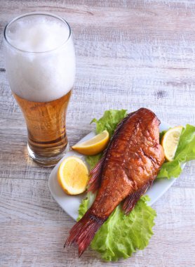 Beyaz arka plan üzerinde izole bira ile balık ve limon yeşil marul yaprakları ahşap kesme tahtası ve cam üzerinde füme.