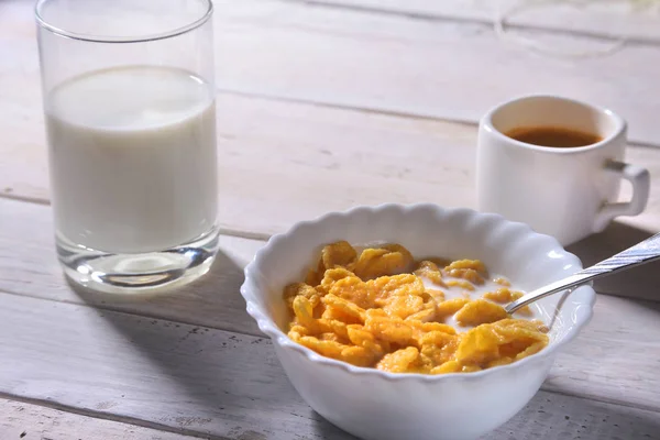 Corn Flakes cereal in a bowl, glass with milk and cap with espresso coffee. Morning breakfast. — Stock Photo, Image