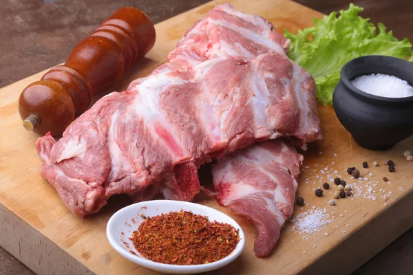 Raw Ribs on a rustic cutting board with salt, pepper and grinder for spices . copy space. Top View. — Stock Photo, Image