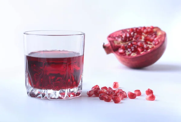 Glas med granatäpple juice granatäpplekärnor och vacker mogen granatäpple på vit bakgrund med plats för kopia utrymme. — Stockfoto