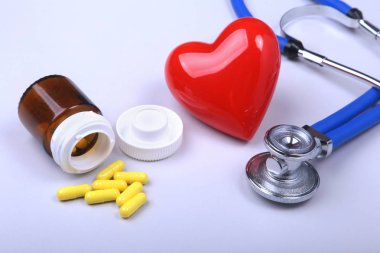 Stetoskop, kırmızı kalp ve metin için yer ile beyaz tabloda çeşitli hap.