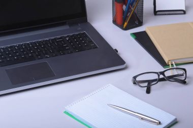 Ofis dizüstü, fare, defter, gözlük, kalem ve masaya döşeme diğer ekipmanlar ile rahat çalışma yerde Close-Up mobilya arka plan bulanıklık.