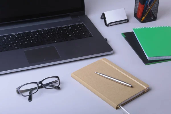 Detail z pohodlné pracovní místo v úřadu s laptop, zápisník, brýle, pera a další vybavení, položení na stůl s kopií prostor. — Stock fotografie