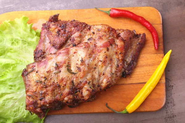 Gegrilde gebarbecued ribben met sla bladeren, hot chili peper en saus op houten snijplank. — Stockfoto