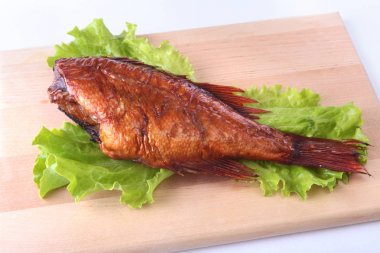 Füme balık ve beyaz arka plan üzerinde izole tahta kesme tahta üzerinde yeşil marul yaprakları limon.