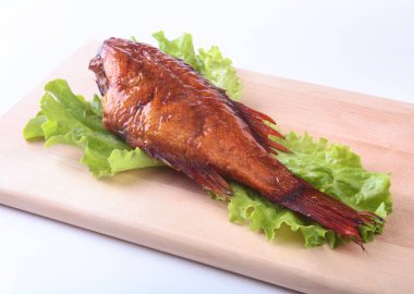 Füme balık ve beyaz arka plan üzerinde izole tahta kesme tahta üzerinde yeşil marul yaprakları limon.