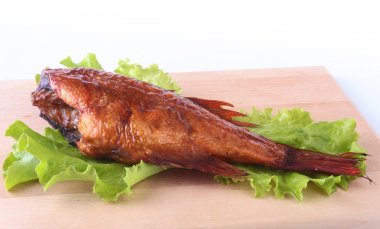 Füme balık ve beyaz arka plan üzerinde izole tahta kesme tahta üzerinde yeşil marul yaprakları limon.