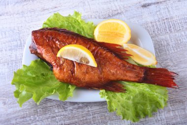 Füme balık ve beyaz arka plan üzerinde izole tahta kesme tahta üzerinde yeşil marul yaprakları limon.