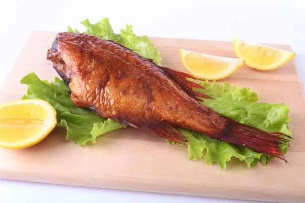 Füme balık ve beyaz arka plan üzerinde izole tahta kesme tahta üzerinde yeşil marul yaprakları limon.