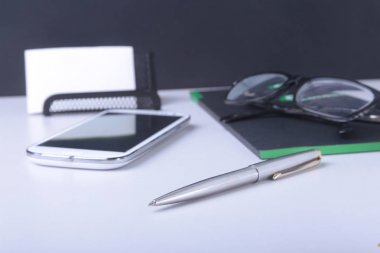 Modern beyaz ofis resepsiyon masası dizüstü bilgisayar, akıllı telefon ve diğer malzemeleri. Giriş metin orta için boş defter sayfası. Üstten Görünüm.