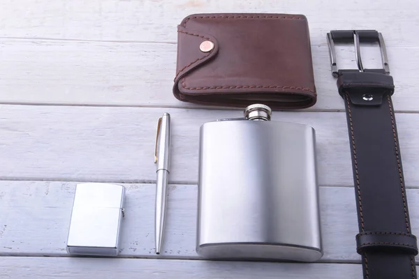 Gadgets and accessories for men on light wooden background. Fashionable men s belt, wallet, lighter, Stainless hip flask and pen. — Stock Photo, Image