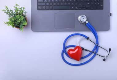 İşyeri dizüstü, stetoskop, Rx reçeteli, gözlük ve kırmızı kalp ve beyaz masa üstünde defter ile doktor. Üstten Görünüm. Kopya alanı.