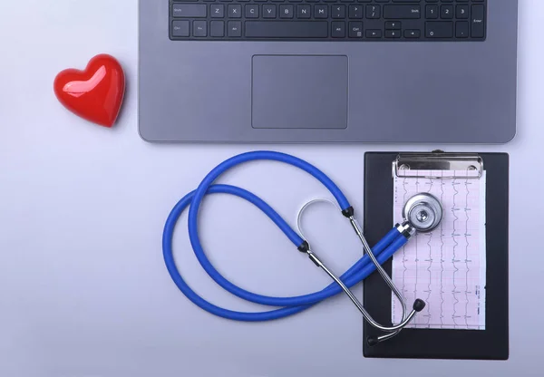 Lugar de trabajo del médico con portátil, estetoscopio, prescripción RX, gafas y corazón rojo y portátil en la mesa blanca. Vista superior. Copiar espacio . — Foto de Stock