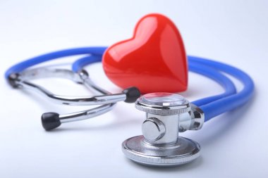 Kırmızı kalp ve beyaz arka planda steteskop.