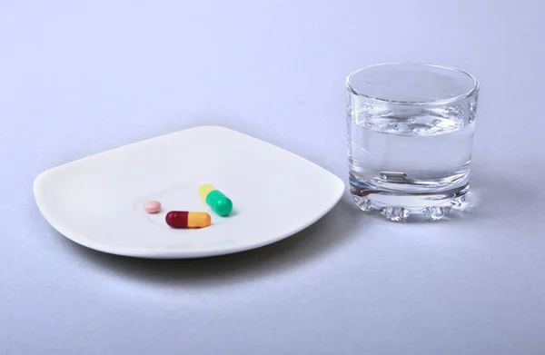 Vaso de agua y pastillas sobre fondo blanco — Foto de Stock