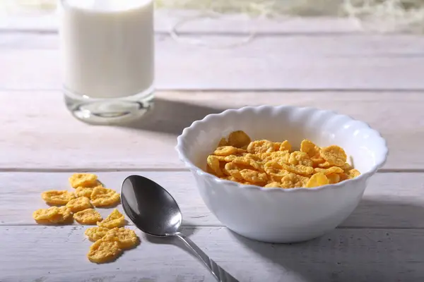 Copos de maíz cereales en un tazón y un vaso con leche. Desayuno por la mañana . —  Fotos de Stock