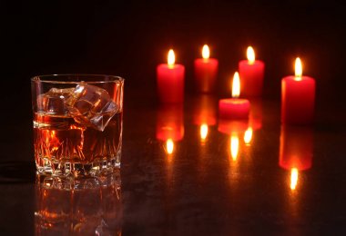 Noel dekorasyonu. ahşap arka plan üzerinde konyak ya da viski ve kırmızı mum bardak.