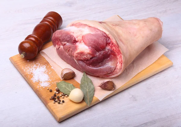 Raw pork knuckle, Aromatic dried bay leaves, garlic, sea salt, pepper grinder and spices on a cutting board. Selective focus. Ready for cooking. — Stock Photo, Image