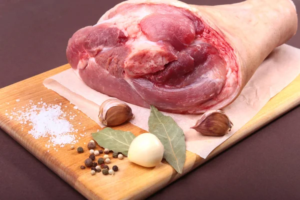 Raw pork knuckle, Aromatic dried bay leaves, garlic, sea salt and spices on a cutting board. Selective focus. Ready for cooking. — Stock Photo, Image