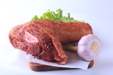 Çiğ domuz knuckle, sarımsak, baharat ve marul yaprakları bir kesme tahtası üzerinde. Seçici odak. Hazır yemek pişirmek için.